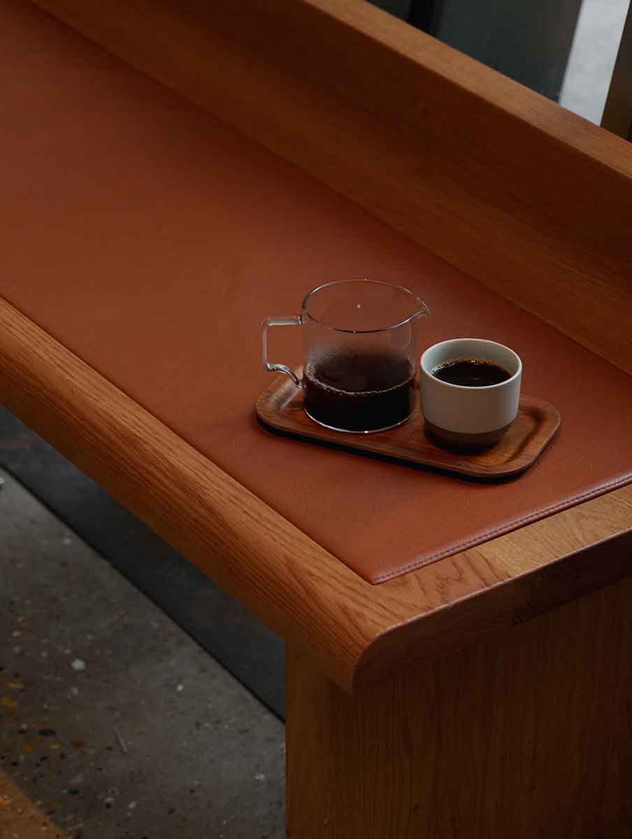Kinto coffee server sitting in a coffee shop next to a cup of coffee